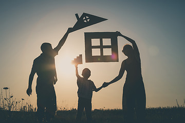 Image showing Happy family standing on the field at the sunset time.