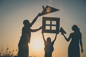 Image showing Happy family standing on the field at the sunset time.