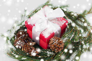 Image showing christmas gift and fir wreath with cones on snow