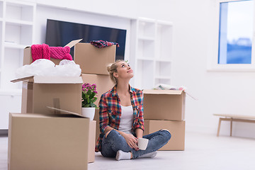 Image showing woman with many cardboard boxes sitting on floor