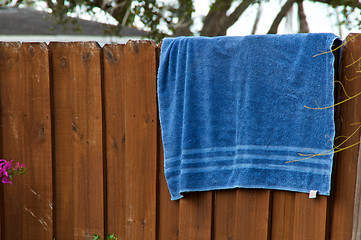 Image showing Blue beach towel hanging on fence