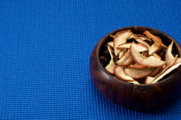 Image showing wooden bowl with dried apple blue background