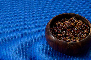 Image showing wooden bowl with homemade raisins blue background