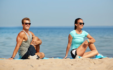 Image showing smiling couple stretching legs on beach