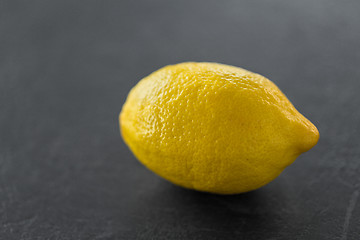 Image showing close up of whole lemon on slate table top