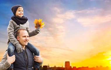 Image showing father carrying son with autumn leaves in city