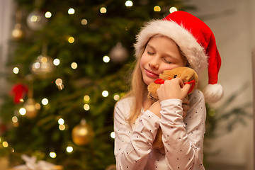 Image showing smiling girl in santa hat with christmas gift