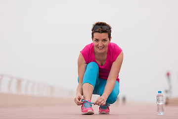 Image showing Young woman tying shoelaces on sneakers