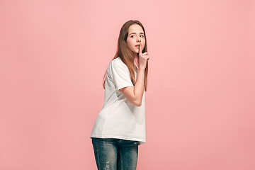 Image showing The young teen girl whispering a secret behind her hand over pink background