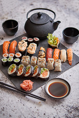 Image showing Assortment of different kinds of sushi rolls placed on black stone board