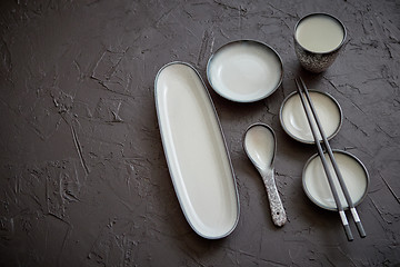 Image showing Set of empty ceramic dishes for sushi and rolls on a black stone table