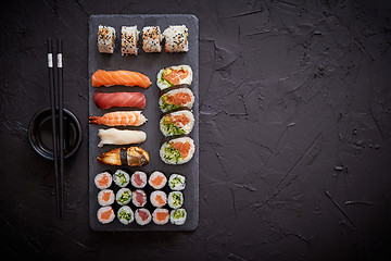 Image showing Sushi rolls set with salmon and tuna fish served on black stone board