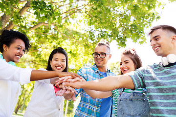 Image showing happy smiling friends stacking hands in park