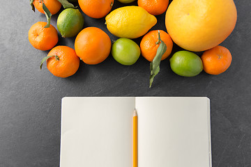 Image showing close up of fruits and notebook on slate table top