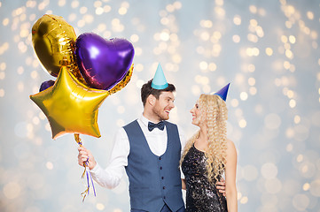 Image showing happy couple in party hats with balloons