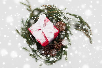 Image showing christmas gift and fir wreath with cones on snow
