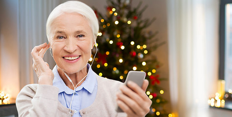 Image showing senior woman with earphones and phone on christmas