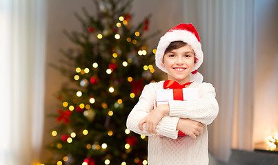 Image showing happy boy in santa hat with gift box on christmas