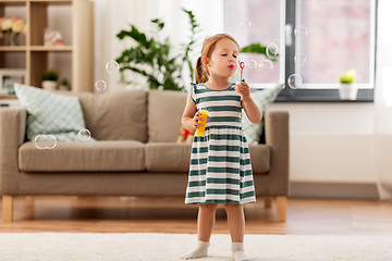 Image showing little girl blowing soap bubbles at home