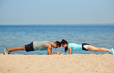 Image showing couple doing plank exercise on summer beach