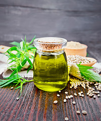 Image showing Oil hemp in jar with flour and grain on dark wooden board