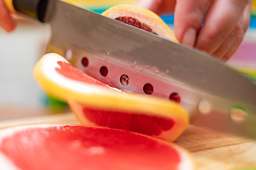 Image showing Women\'s hands Housewives cut with a knife fresh grapefruit on th