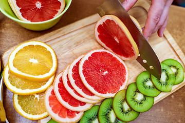 Image showing Women\'s hands Housewives cut with a knife fresh grapefruit on th