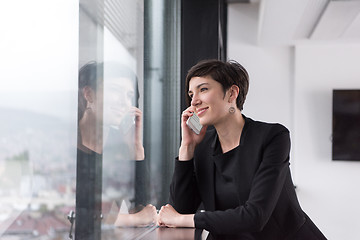 Image showing Elegant Woman Using Mobile Phone by window in office building