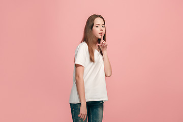 Image showing The young teen girl whispering a secret behind her hand over pink background