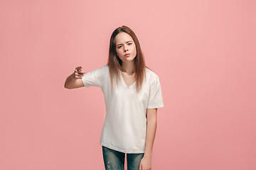 Image showing The happy teen girl pointing to you, half length closeup portrait on pink background.