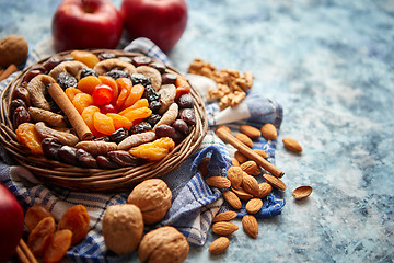 Image showing Composition of dried fruits and nuts in small wicker bowl placed on stone table