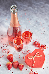 Image showing Bottle of rose champagne, glasses with fresh strawberries and heart shaped gift