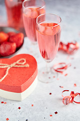 Image showing Bottle of rose champagne, glasses with fresh strawberries and heart shaped gift