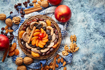 Image showing Composition of dried fruits and nuts in small wicker bowl placed on stone table