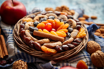 Image showing Composition of dried fruits and nuts in small wicker bowl placed on stone table