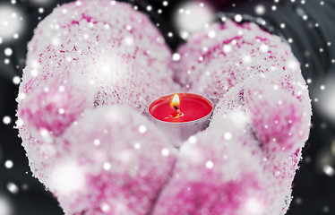 Image showing close up of hands in winter mittens holding candle