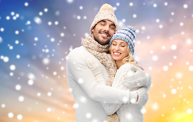 Image showing happy couple in winter clothes hugging over snow