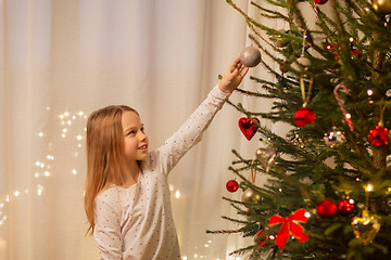 Image showing happy girl in red dress decorating christmas tree