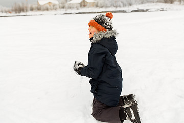 Image showing happy little boy playing with snow in winter