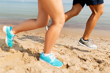 Image showing legs of sportsmen in sneakers running along beach