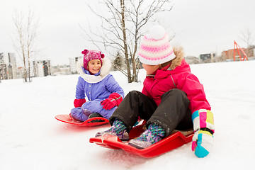 Image showing happy little girls on sleds outdoors in winter
