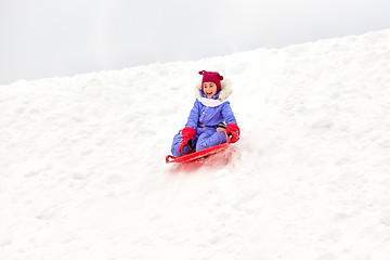 Image showing girl sliding down on snow saucer sled in winter