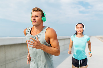 Image showing couple with headphones running outdoors