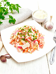 Image showing Salad of surimi and tomatoes with mayonnaise on light wooden boa