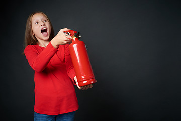 Image showing Girl holding red fire extinguisher directing at blank copy space