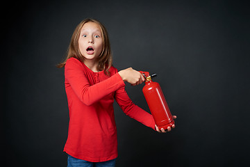 Image showing Girl holding red fire extinguisher directing at blank copy space