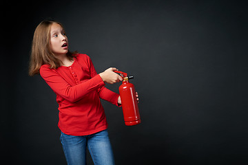 Image showing Girl holding red fire extinguisher directing at blank copy space