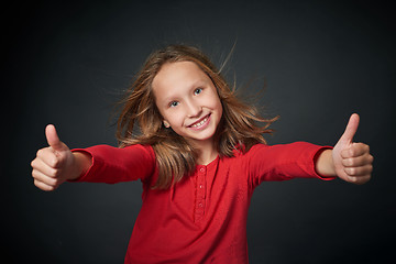 Image showing Happy girl gesturing thumbs up hand sign