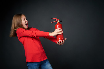 Image showing Girl holding red fire extinguisher directing at blank copy space