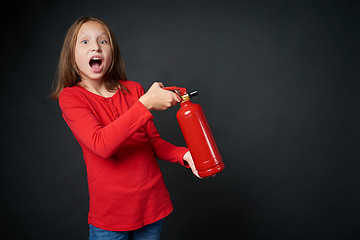 Image showing Girl holding red fire extinguisher directing at blank copy space